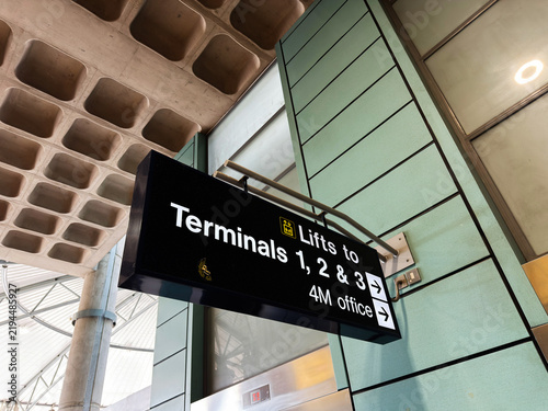 Airport sign pointing to lifts to Terminals 1 2 and 3 with modern terminal architecture and elevators