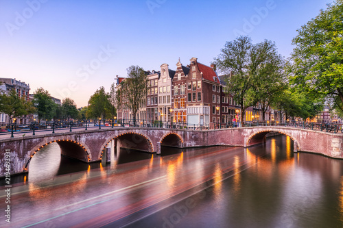 Illuminated Amsterdam Canal Houses and Bridge at Sunset