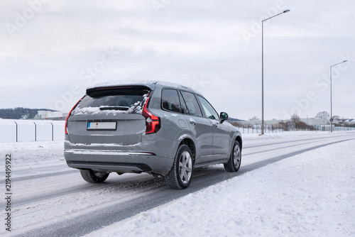 Graues Auto fährt auf einer verschneiten Straße im Winter.