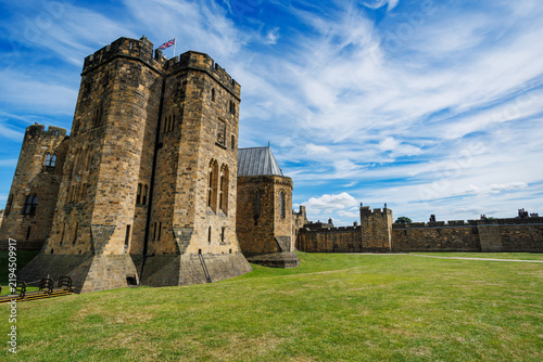 Historic English Alnwick castle with towers on grassy ground, UK