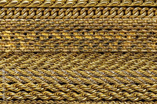 Close-up of assorted gold-colored metal chains with different link shapes, sizes and weaving patterns.