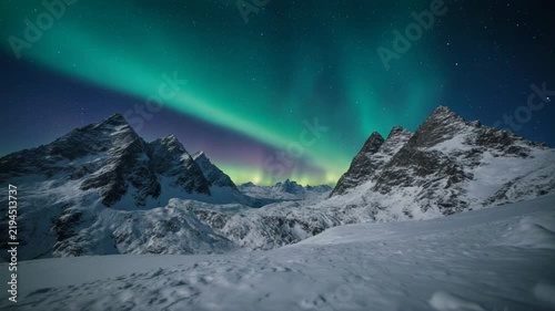 Northern Lights dancing above snow-covered mountains during a clear winter night with subtle camera movement