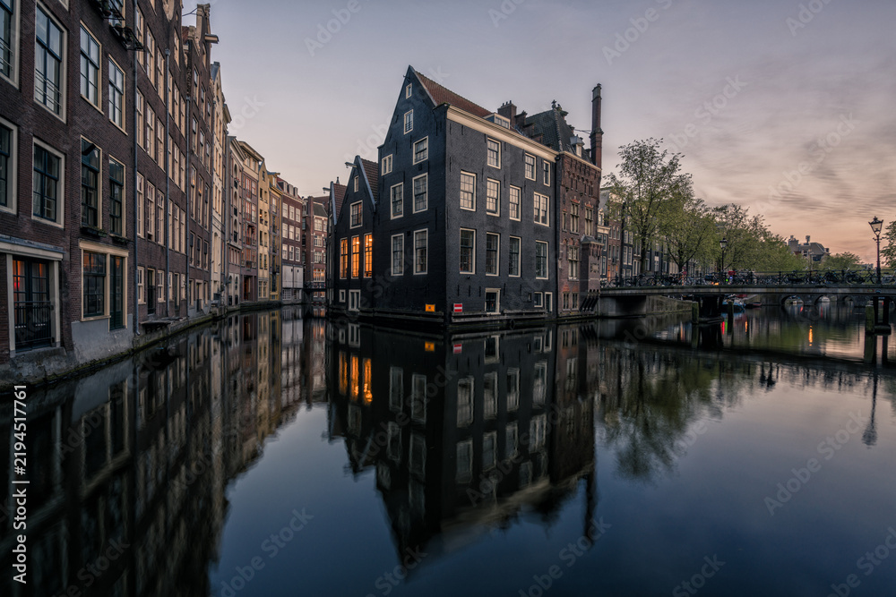 Fototapeta premium Traditional Amsterdam canal houses reflected in water at blue hour