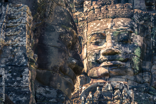 Photography Close up of two giant stone faces at Bayon temple, side and frontal view in Angk