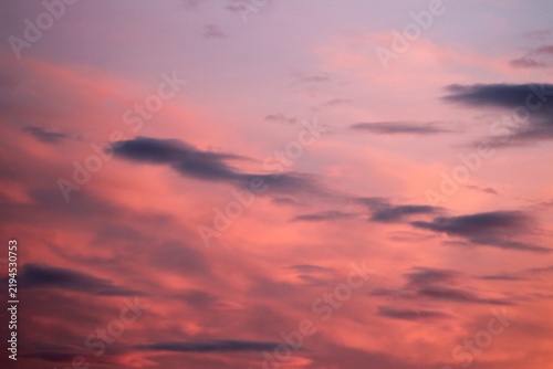 Soft pastel clouds illuminated by the setting sun across a vibrant evening sky, forming a peaceful atmospheric background for nature, travel, weather, and design concepts