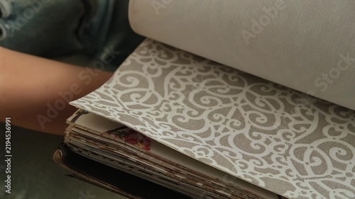 Close up of a female hand browsing fabric samples to choose material for roller blinds for home Interior design and window treatment concept focused on selecting colors textures and fabrics for decor