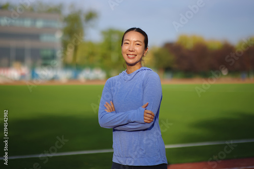 Фотография Asian sportswoman with crossed arms confidently smiling on an outdoor running tr