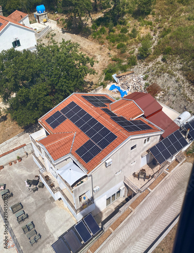 High-angle view of a modern house equipped with numerous solar panels on its terracotta tile roof
