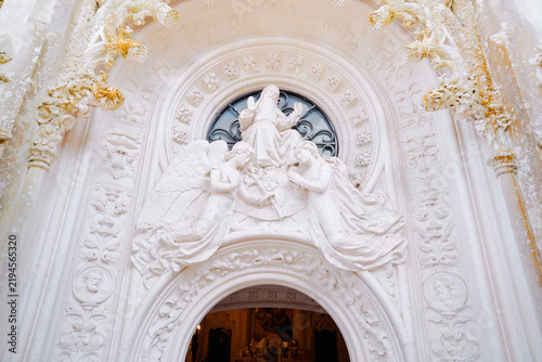 Принти на полотні Ornate white stone relief featuring angels and a seated religious figure above a carved church entrance, showcasing detailed architectural sculpture, historic decoration and devotional craftsmanship