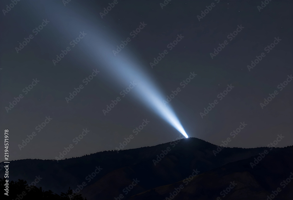 Obraz premium Guidance and hope concept bright searchlight beam shining from mountain peak into dark night sky vision leadership and future direction