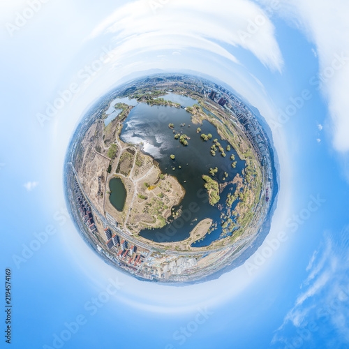 Foto A tiny planet aerial panorama showing a wetland lake with islands, adjacent urban areas under a clear sky