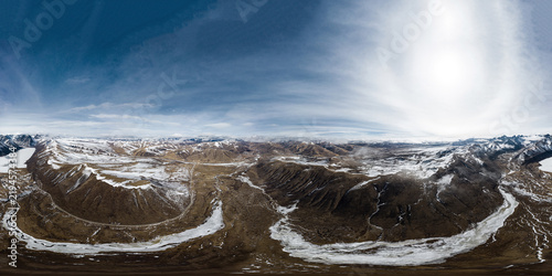 Foto A wide panoramic view of a high-altitude valley with snow-dusted mountains, winding rivers, and clear blue sky