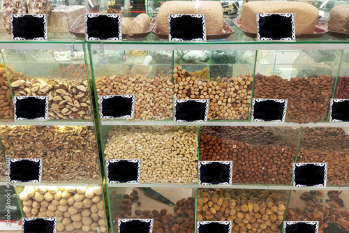 Loose nuts in a glass shop display case, and halva. Blank black price tags.