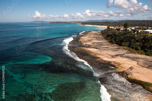 Idyllic aerial view from the Pacific Lookout looking south to the scenic Racecourse Beach and Dolphin Point. Captured on a sunny day from high above Racecourse headland on the South Coast, NSW.