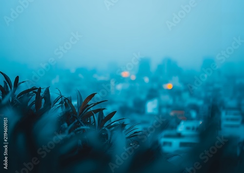 Abstract moody city background with blurred buildings and dark teal foliage for minimalist environmental design