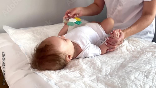 Mother gives teether toy to infant baby,developing pincer grasp, focused attention.Physical therapist exercising newborn little child,motherhood,baby care,wellness
