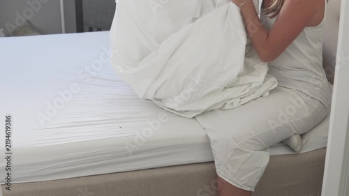 Woman making a bed with fresh clean white bedding at home. Changing bed linen and arranging a duvet in a bright bedroom, housekeeping and domestic routine concept
