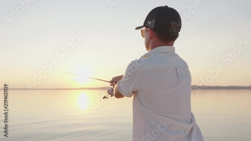 Young man fishing on the river during sunset and casts a lure