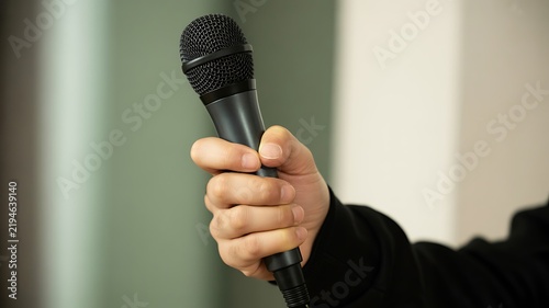Hand holding a microphone for an interview, speech, presentation, or media event