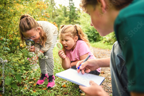 happy school kids learning about environment and insects during field trip with camp monitor