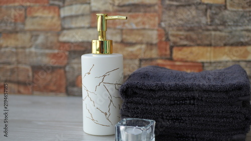 Quadro su tela Stacked dark gray towels placed next to a tealight candle and a soap dispenser; spa-style setting