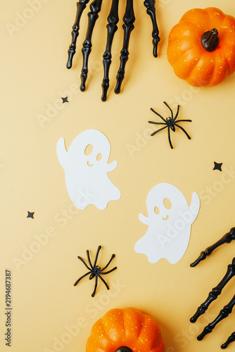 Foto Spooky Halloween theme with pumpkins, ghosts, spiders, and skeleton hands on a pale orange background
