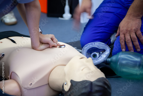 Two hands performing chest compressions on a human mannequin
