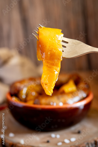 Sausages with yellow peppers in terracotta bowl