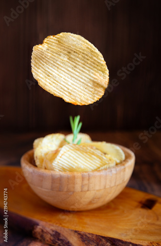 Crunchy potato chip floating over savory snack bowl