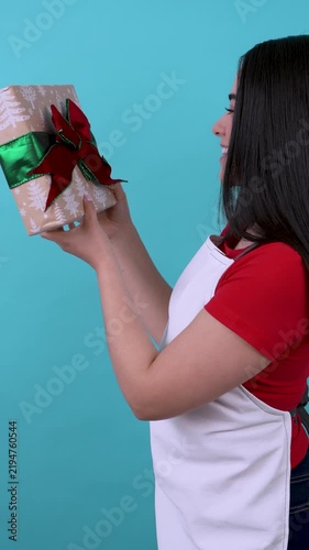 Happy hispanic shop assistant holding wrapped christmas present