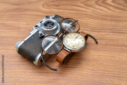 Fotografie Vintage film camera with old eyeglasses and antique wristwatch on wooden table