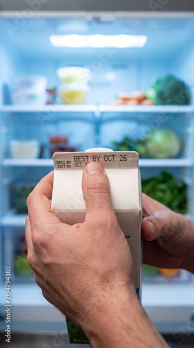 Person checking the expiration date on a milk carton.