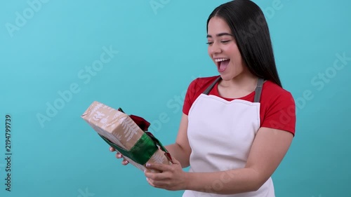 Happy hispanic young woman receiving and shaking a christmas gift