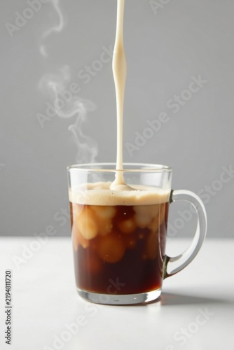 Creamy Liquid Pouring into a Mug of Dark Beverage Creating a Swirling Effect