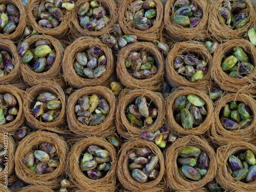 Various baskets filled with pistachios and surrounded by thin layers of pastry