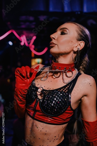 Portrait of a go-go dancer in red and black jeweled stagewear with glossy gloves and choker under nightclub neon, ideal for nightlife, fashion, dance and event promotion