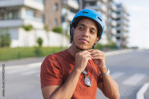 Man adjusts safety helmet while preparing to ride a bicycle in the city