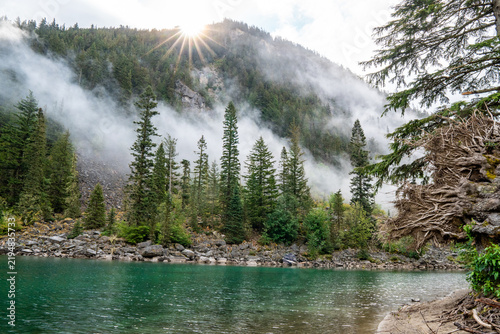 Incredible sunrise over a lake with mountains and a Canadian pine forest.