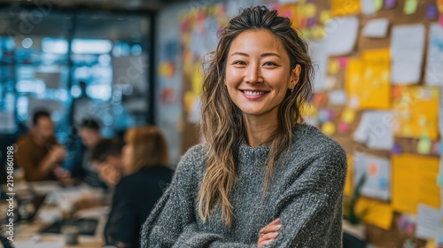 Smiling young woman with long wavy hair in a casual sweater in a creative office environment