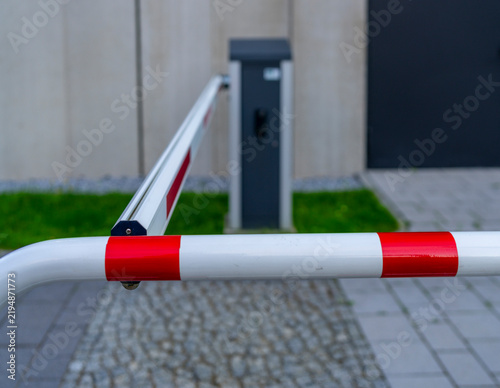 Fotografie Automatische Schrankenanlage mit rot-weißer Warnmarkierung und einer dahinter be