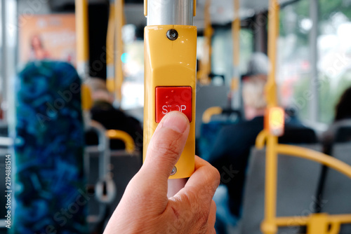 a man presses the red stop button on a city bus