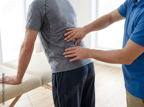 Physiotherapist examining patient s lower back during a manual therapy session