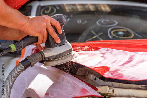 Grinder in the hands of a man who sharpen a car varnish in the car shop.