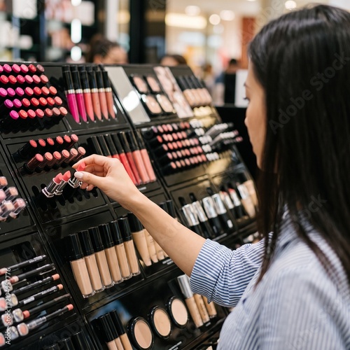 Customer choosing lipstick at a cosmetics display in a beauty store
