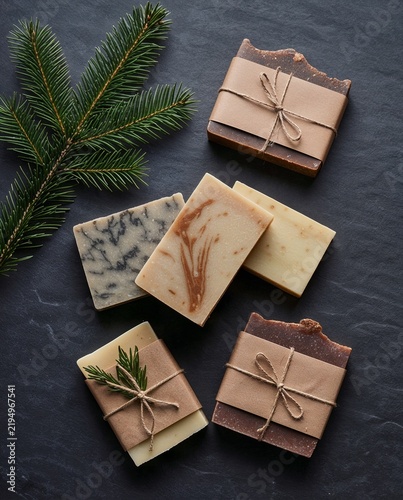 Natural handcrafted soap bars with greenery on a dark stone surface  