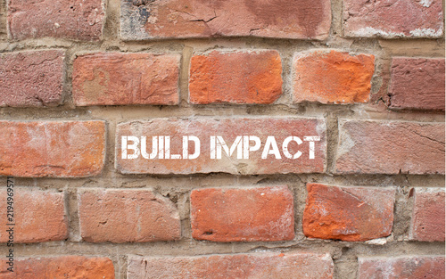 Foto Build impact text painted on brick wall