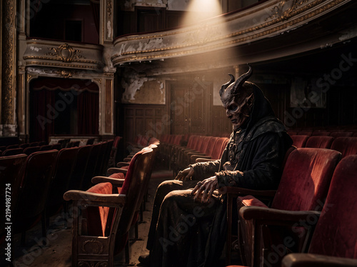 Mysterious masked figure sits alone in an empty, decaying theater