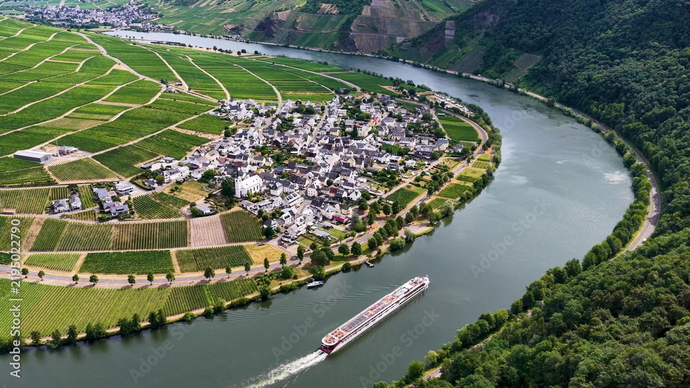 Obraz premium Luftaufnahme der malerischen Moselschleife bei Minheim mit einem eleganten Flusskreuzfahrtschiff auf dem Wasser, umgeben von grünen Weinbergen im Sommer.