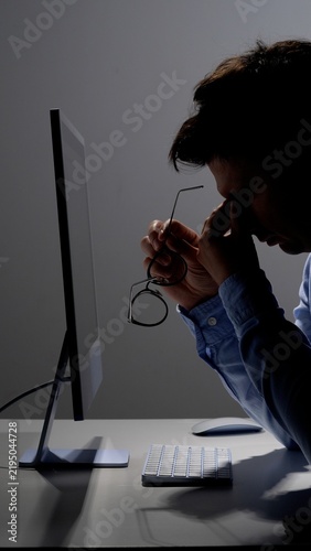 Canvastavla Overworked man sitting at his desk late at night, holding his glasses and rubbin