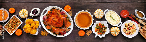 Thanksgiving turkey dinner. Top view table scene on a rustic dark wood table banner background. Turkey, mashed potatoes, stuffing, pumpkin pie and sides.